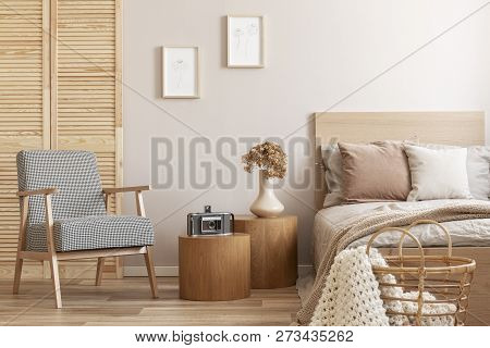 Trendy Retro Armchair Next To Two Round Wooden Tables With Vintage Camera And Vase With Flowers In B