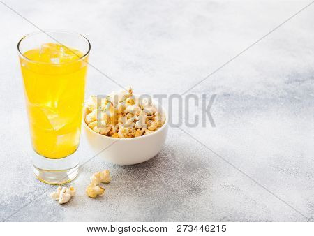 Glass Of Orange Soda Drink With Ice Cubes And Whitel Bowl Of Popcorn Snack On Stone Kitchen Backgrou