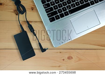 Adapter Power Cord Charger Of Laptop Computer On Wooden Floor,top View