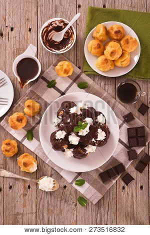 Chocolate Profiteroles With Whipped Cream On White Dish.