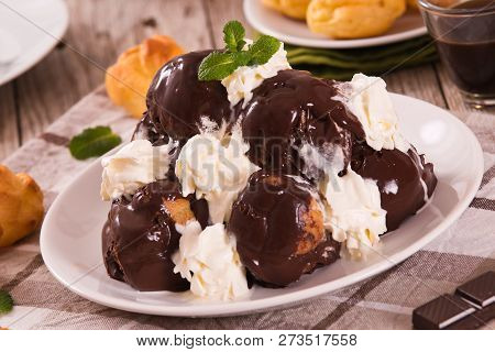 Chocolate Profiteroles With Whipped Cream On White Dish.