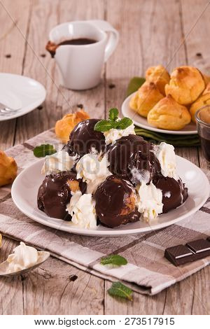 Chocolate Profiteroles With Whipped Cream On White Dish.