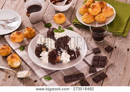 Chocolate Profiteroles With Whipped Cream On White Dish.