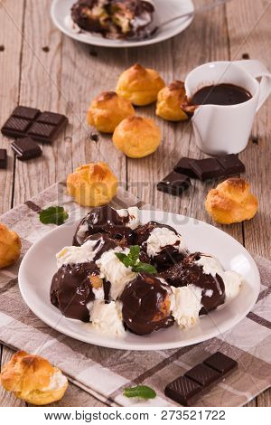 Chocolate Profiteroles With Whipped Cream On White Dish.