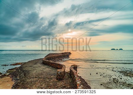 Old Birck Rock Jetty Near Coastline At Sunset.