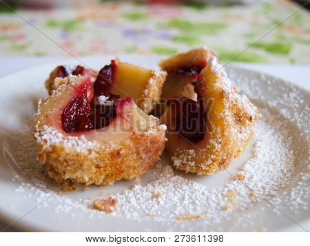 Plum Dumpling With Powdered Sugar On A White Plate.