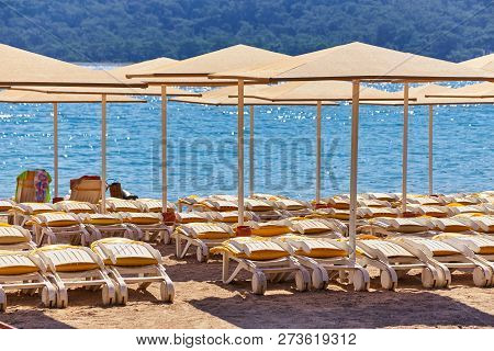 Umbrellas And Empty Beach Chairs On The Beach Near Blue Sea Water, Kemer, Turkey, Mediterranean Sea.