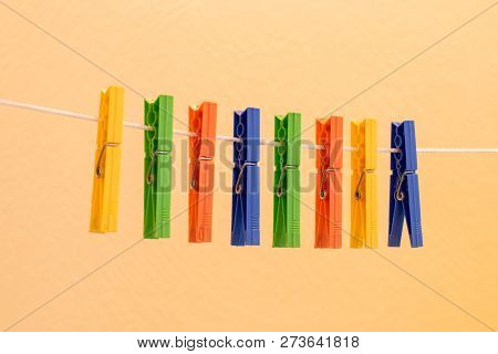 Colorful Clothespins Hanging On Clothesline On White Background