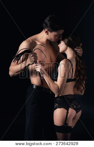 Seductive Undressed Couple Holding Leather Flogging Whip Isolated On Black