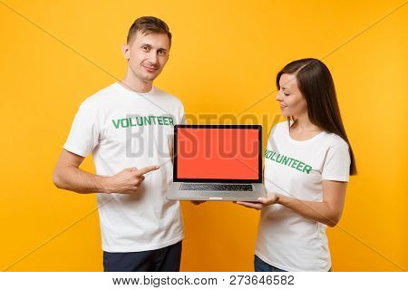 Colleagues Couple In White T-shirt Inscription Volunteer Hold Laptop Pc Computer, Blank Empty Screen