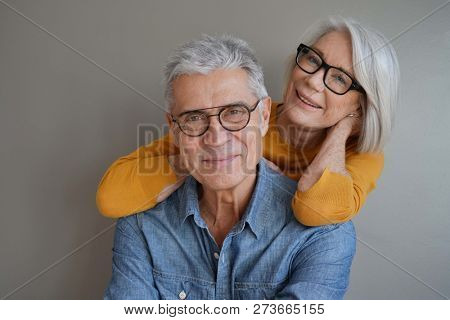  Portrait of relaxed fun senior couple wearing glasses on background                              