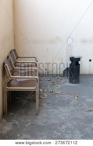 A Close Up Front View Of Three Brown And Cream Connected Seats Outside In A Designated Smoking Area 