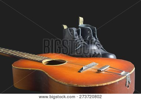Rock And Roll Concept. Black Boots And Acoustic Guitar. Rock And Roll Boots On Black Background.