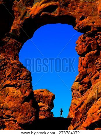 Silhouette of hiker in arch canyon rock formations