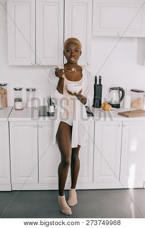 African American Woman Eating Cornflakes In White Litchen