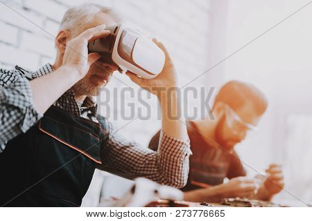 Man Checking Virtual Reality Glasses In Repair Shop. Worker With Tools On Background. Computer Hardw