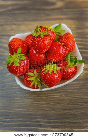 A Small White Porcelain Bowl Filled With Juicy Fresh Ripe Red Strawberries. Textured Table Top. Fres