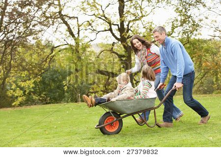 Parents Giving Children Ride In Wheelbarrow