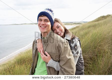 Young Couple Walking Through Sand Dunes Wearing Warm Clothing