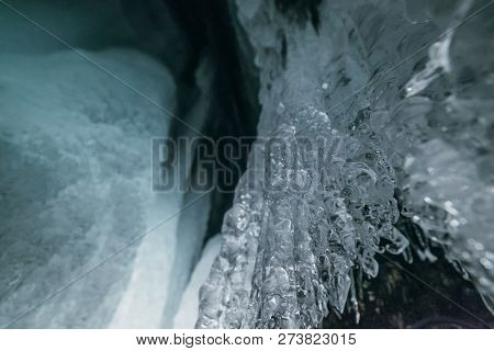Winter Baikal. Olkhon Island. Ice Grotto. Thick Blue Ice And Icicles On The Coastal Rocks Of Olkhon 