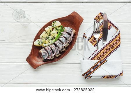Marinated Herring, Potatoes And Onions In Earthenware Plate With Glass Of Vodka, Cutlery And Embroid