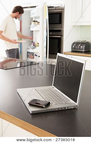 junger Mann Befestigung Snack in Küche mit Laptop in moderne Küche
