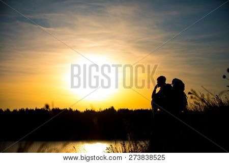 Young Man With A Backpack, Enjoying The Sunset On Top Of The Mountain. Tourist Traveler.