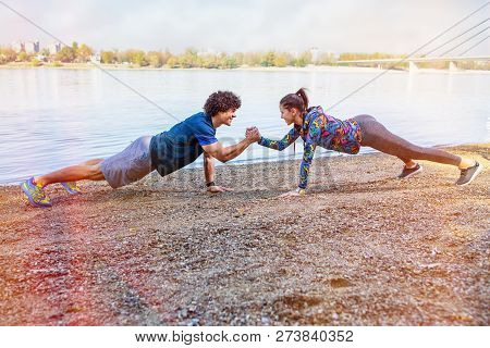 Exercise - Sportswoman And Sportsman Giving High Five To Each Other While Doing Push-ups Outdoors