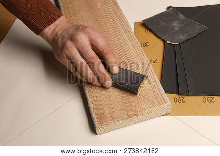 Man Hand Smoothing Wood Board Using Sandpaper. Sanding And Polishing Wood Larch Plank.