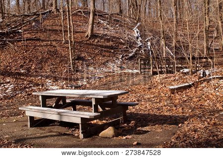 A Wooden Picnic Table Partially Covered In Snow Next To A Wooden Bridge In The Winter Woods In Frick