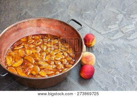 Fresh Bright Peaches And Nectarins Lay On The Kitchen Desk Close To The Copper Jar, Full Of Peach Ja