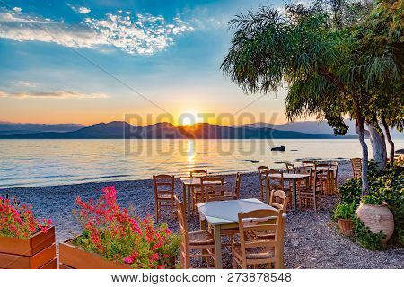 Romantic Scene With Table And Chairs On A Terrace Outdoor, Illuminated By Sunrise Light, In Lefkada 