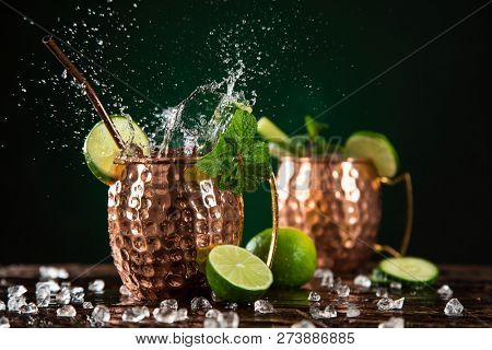 Famous splashing Moscow mule alcoholic cocktail in copper mugs, freeze motion effect.