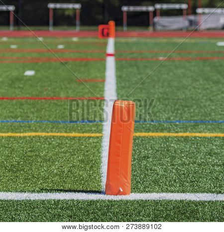 A Green Turf Football Fields Goalline Is Marked With Orange Pylons , A White Line And An Orange Sign