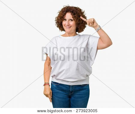 Beautiful middle ager senior woman wearing white t-shirt over isolated background Smiling pointing to head with one finger, great idea or thought, good memory