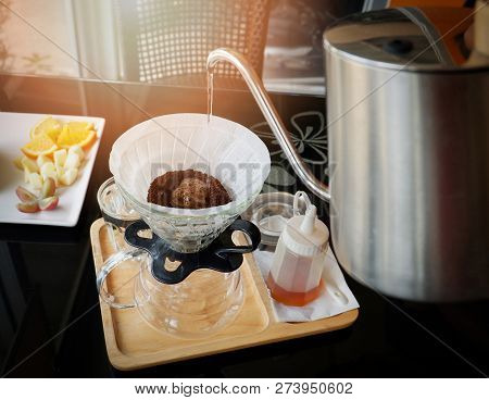 drip coffee barista pouring water on filtered coffee drip brewing / make cup hand drip coffe filtered in glass jar on tray wooden black table cafe shop
