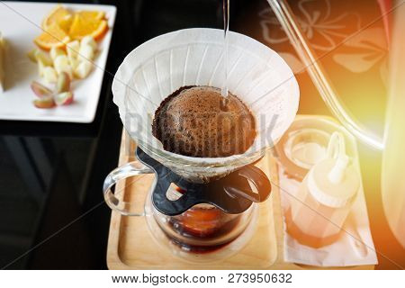 drip coffee barista pouring water on filtered coffee drip brewing / make cup hand drip coffe filtered in glass jar on tray wooden black table cafe shop