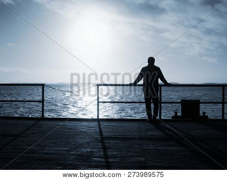 Old Man Watch The Morning Sea Over Pier Handrail.  Man On The Sea Bridge Looking At The Baltic Sea I
