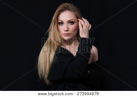 Sexy Lady Diva With Long Blonde Hair In Long Coat Posing In Studio, Dark Background. Elegant Woman. 