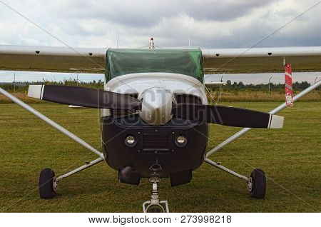 The One Engine Plane Stands On The Green Grass In A Cloudy Day. Front View Of Plain. A Small Private