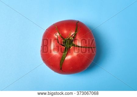 Whole Appetizing Red Tomato On A Blue Background.