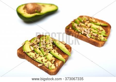 Toast With Avocado Slices, A Mixture Of Seeds On A White Background. Healthy Snack Tomorrow. The Con