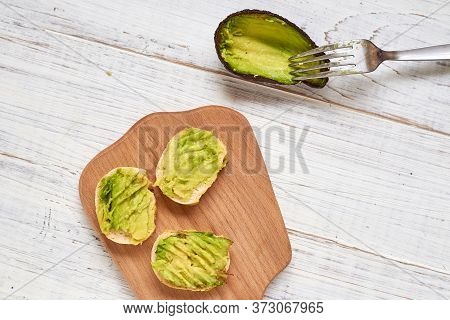 Baguette, Bruschetta, Canapes With Avocado On A Light Wooden Background.