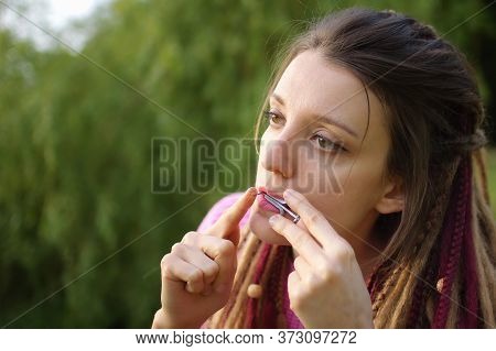 Close-up Outdoors Portrait Of Young Female Shaman In Pink Knitted Sweater With Long Dreadlocks Playi