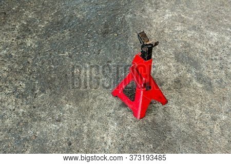 Red Axle Stand On Floor. Red High Lift Jack Stand On The Floor. Red Extendable Jack Stands Are Used 