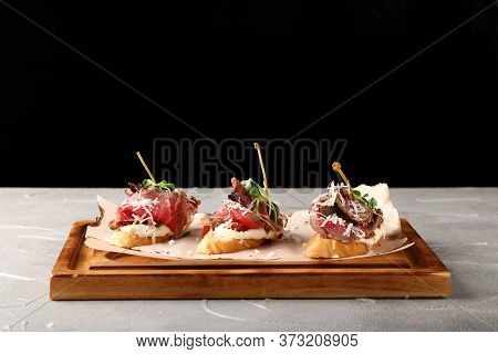 Set Of Traditional Spanish Tapas With Beef On Wooden Deck And Black Background. Topas Or Bruschetta 