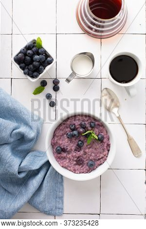 Blueberry Oatmeal For Breakfast Ith Coffee On White Table Overhead Shot