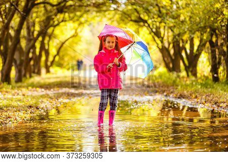 Adorable Toddler Girl With Colorful Umbrella Outdoors At Autumn Rainy Day