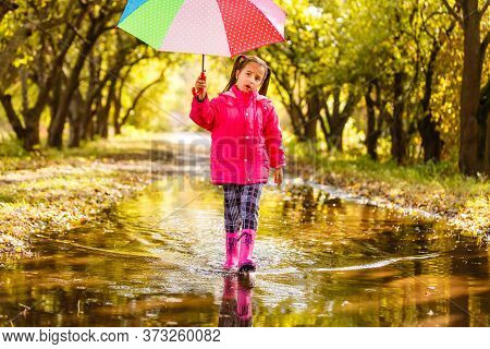 Adorable Toddler Girl With Colorful Umbrella Outdoors At Autumn Rainy Day