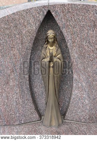 Sint Gillis Waas, Belgium, July 9, 2019, Light Copper Statue In A Marble Niche Represents The Prayin